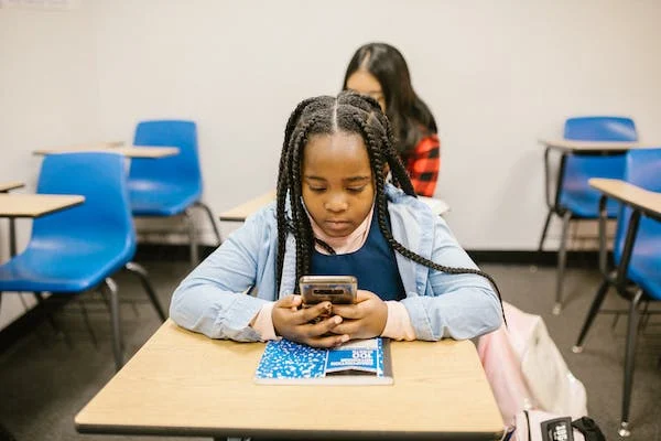 Kid-using-phone-Kid-using-phone-in-her-desk