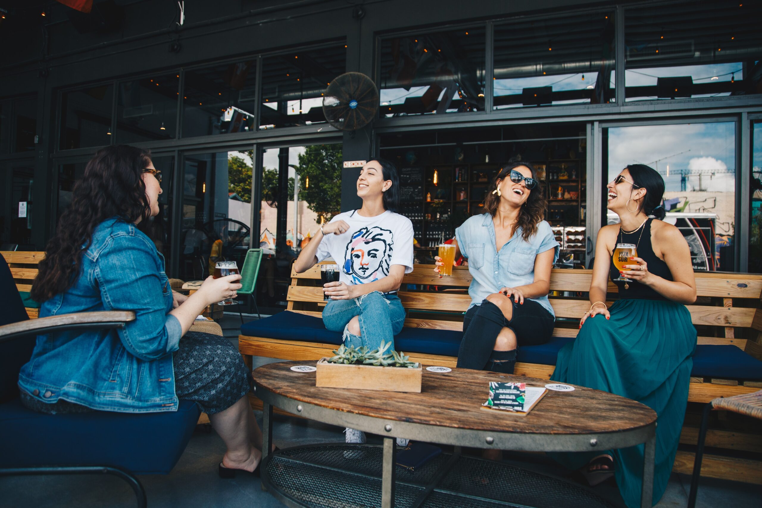 four-women-chatting-while-sitting-on-bench