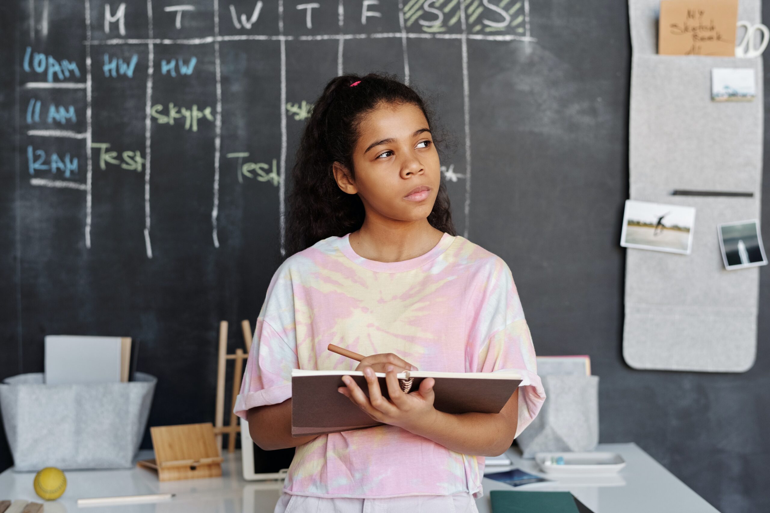 woman-in-pink-and-yellow-crew-neck-t-shirt-holding-brown-notebook